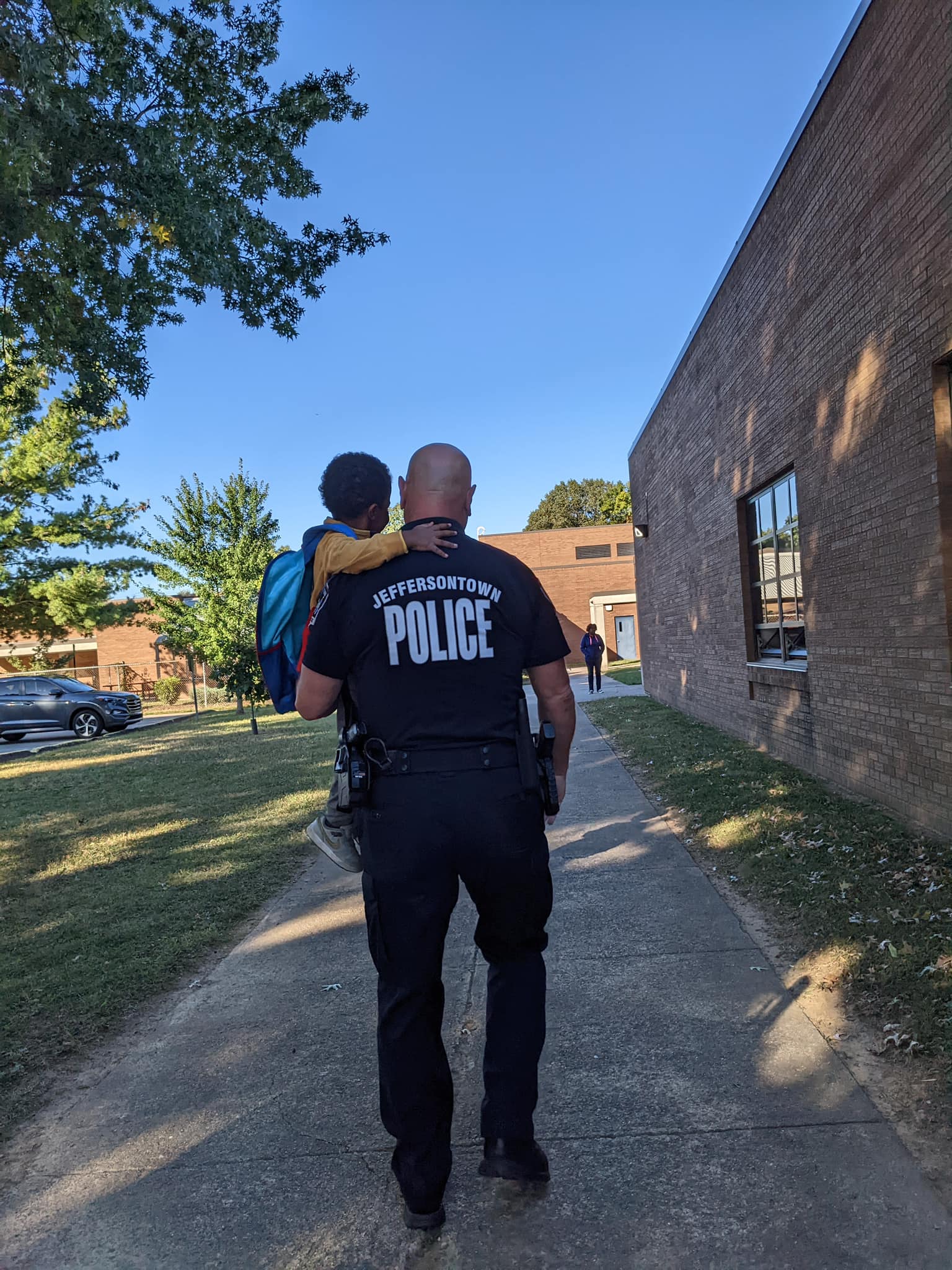 Jeffersontown Police officer carrying a child outside a school